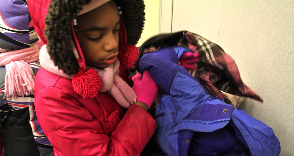 Aniyah Jones, 9, searches through a pile of coats at the East Harlem Asthma Center of Excellence. New York Cares, which organizes an annual citywide coat drive, is facing a shortage of coat donations in a winter with below-average temperatures. (Joanna Plucinska/NY City Lens)