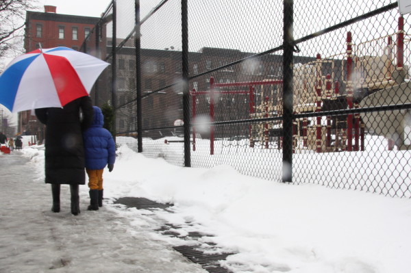 A mother and her son walk nearby PS87 on 78th street and Columbus Avenue. The school remained open today and did not cancel any classes. However, students could not use the playground as it was not cleared of snow and children watched a movie in the auditorium instead of playing outside.