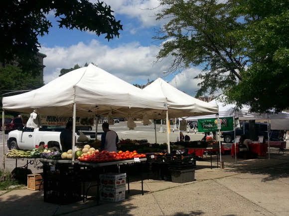 White canopy tents shield fresh produce at the weekly Farmers' Market outside Bronx Community College