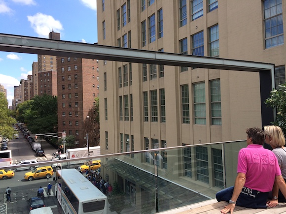 Two people look out over the street from a viewing gallery at the High Line park