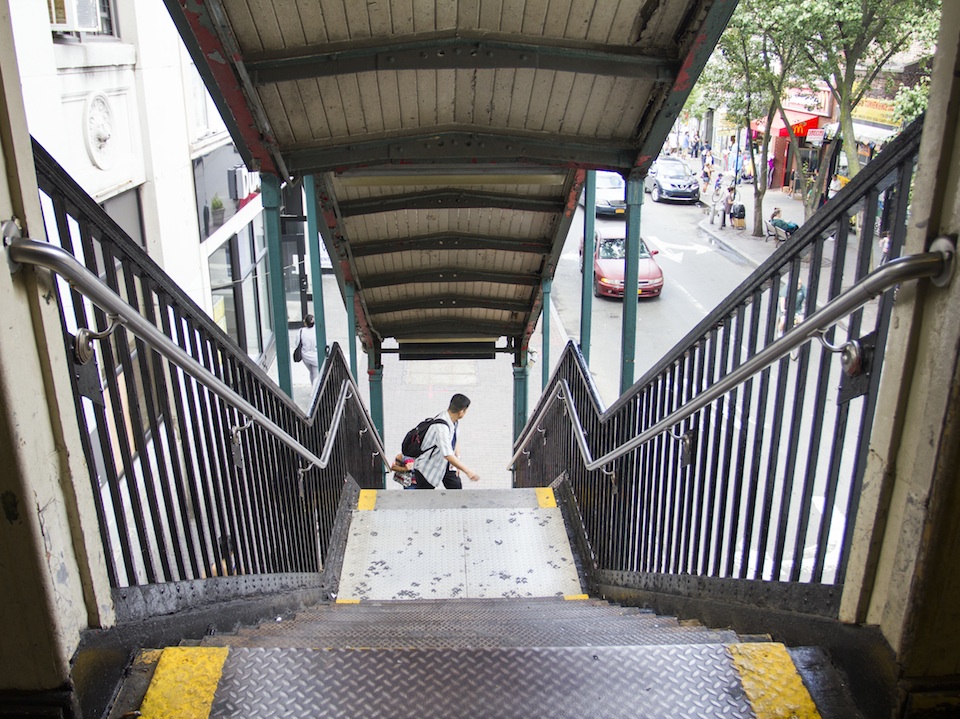 A man helps a woman with a child up the stairs at the 82nd St. Station in Jackson Heights (Marissa Armas/ NY City Lens).