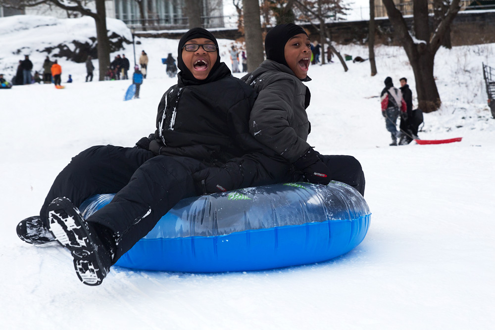 Brandon Nesbith, 10, and Jamie Nesbith, 11, slide down the snow-covered hill on an inflated tube.
