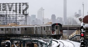 Part of the Manhattan skyline can be seen as a Flushing-bound 7 train arrives at Queensboro Plaza station after limited subway service was restored following a winter storm, Tuesday, Jan. 27, 2015, in the Queens borough of New York. Gov. Andrew Cuomo says a snowstorm-related New York City area travel ban is lifted, except for Suffolk County on Long Island. (AP Photo/Jason DeCrow)
