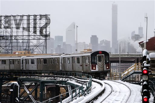 Part of the Manhattan skyline can be seen as a Flushing-bound 7 train arrives at Queensboro Plaza station after limited subway service was restored following a winter storm, Tuesday, Jan. 27, 2015, in the Queens borough of New York. Gov. Andrew Cuomo says a snowstorm-related New York City area travel ban is lifted, except for Suffolk County on Long Island. (AP Photo/Jason DeCrow)