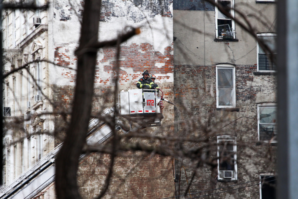 Firefighters in a cherry picker near the East Village explosion site . (Solange Uwimana / NY City Lens)