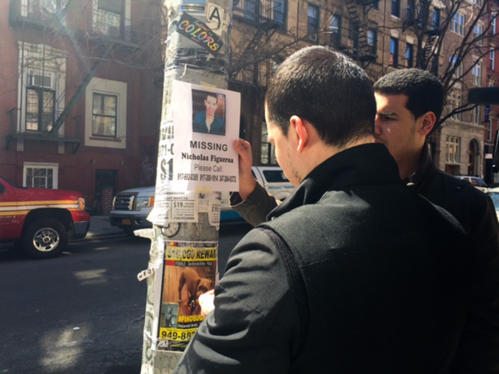 Relatives and friends of Nicholas Figueroa put up fliers near the explosion site on March 29. (Solange Uwimana /NY City Lens)