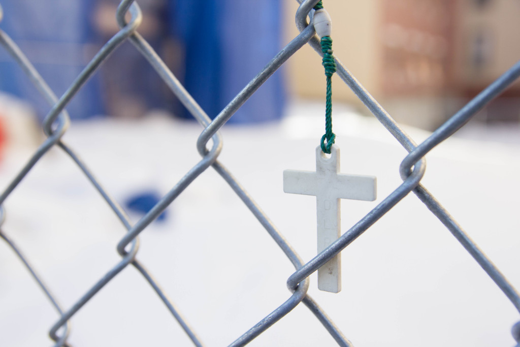 A rosary is woven through the chain link fence at the site of the explosion. (Justine Calma/NY City Lens)
