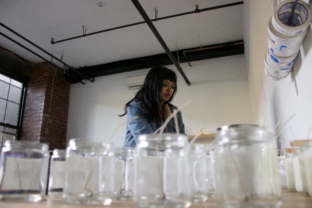 Surrounded by empty candle jars, Tanwi Nandini Islam liquefies wax, on Oct. 21, 2015, in Brooklyn.