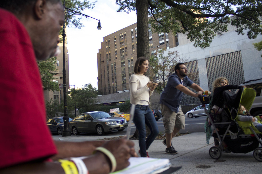 Stephon X looks on at a family on West 110th Street, New York. Photo: Oliver Arnoldi
