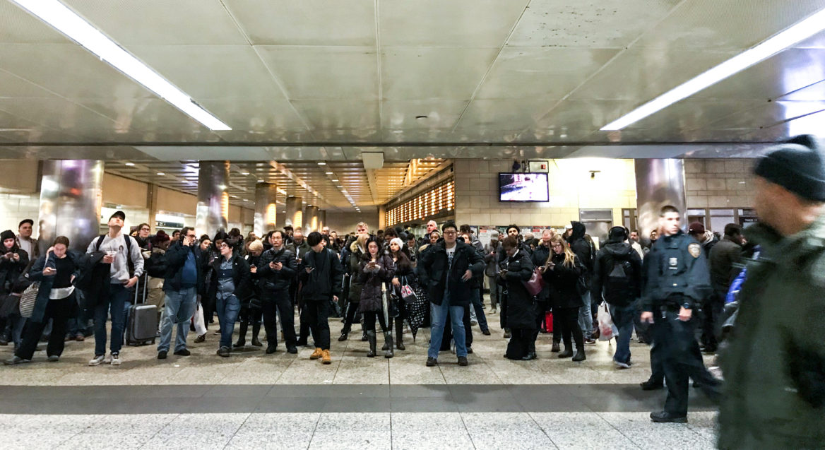 Travelers wait in Penn Station after weather delays prompted the Long Island Rail Road to cancel trains. (Angie Wang for NY City Lens)