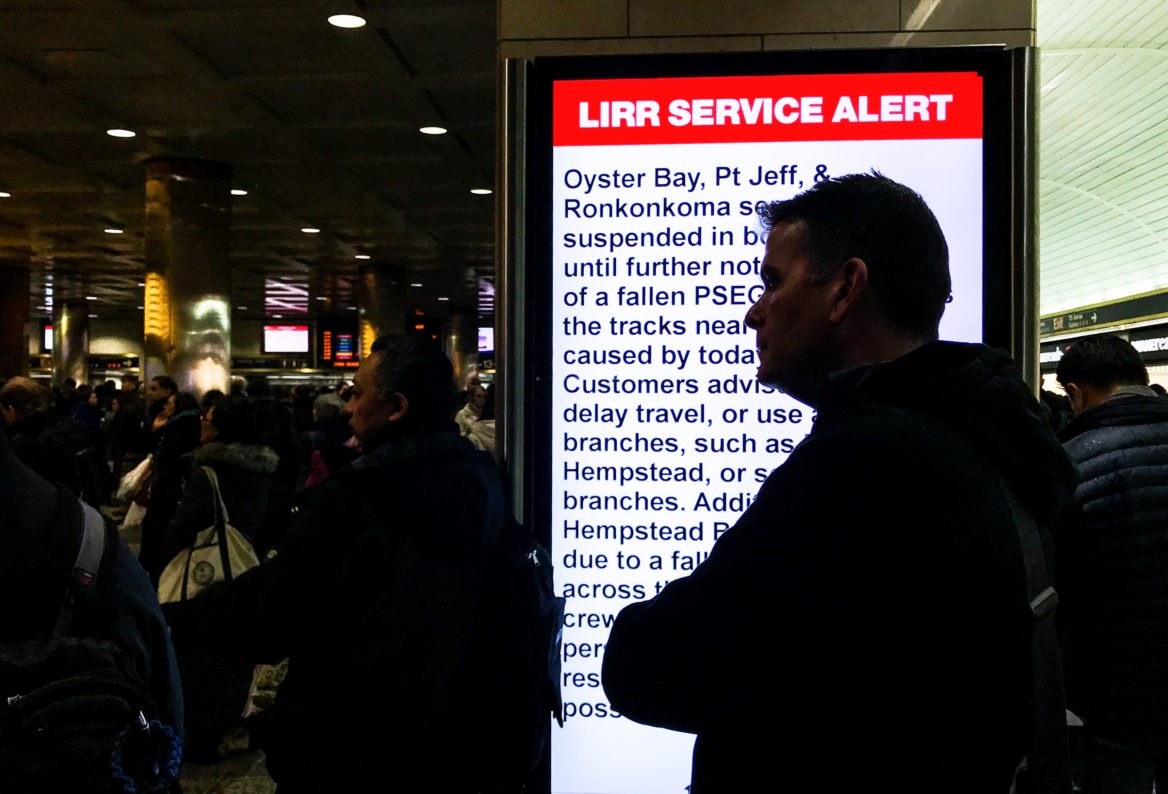 A man waits to board his train amid delays in midtown Manhattan's Pennsylvania Station. (Angie Wang for NY City Lens)