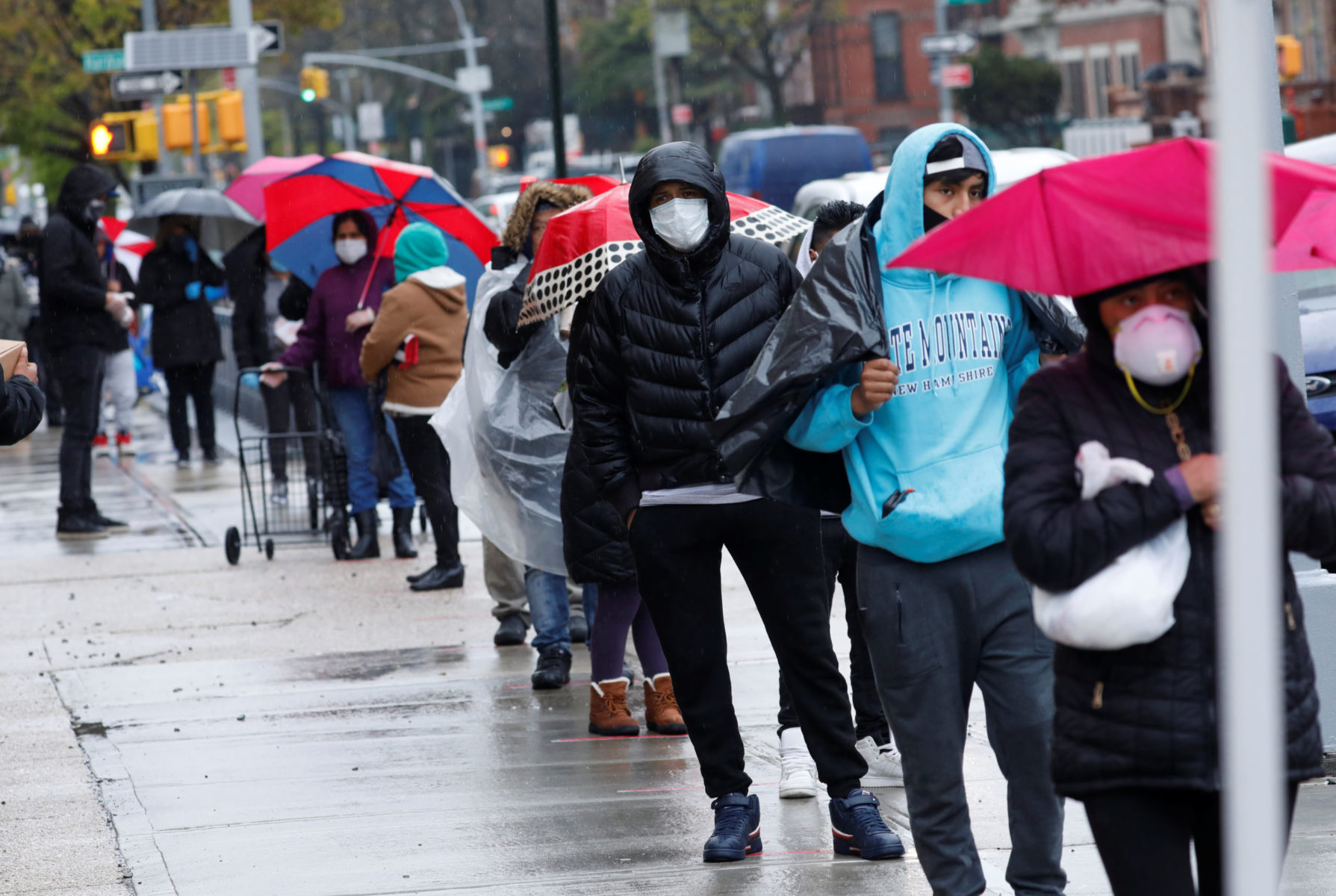 People wear protective face masks as they wait in line to receive free food at a curbside pantry in Brooklyn during the COVID-19 outbreak. / Photo by Mike Segar for REUTERS