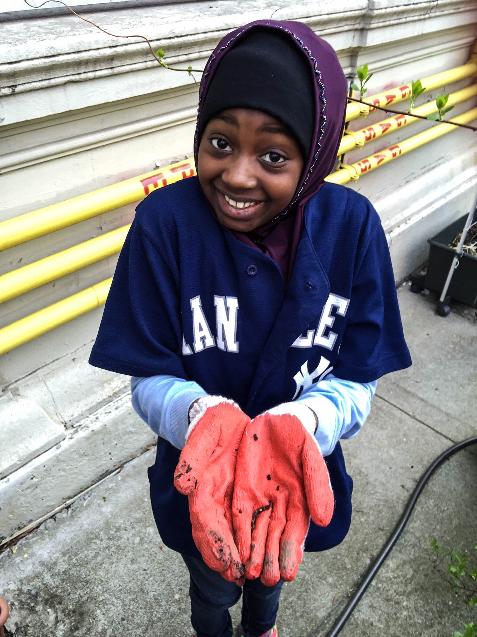 Student holds worm during community compost planting session at Benjamin Franklin School at P.S. 55 