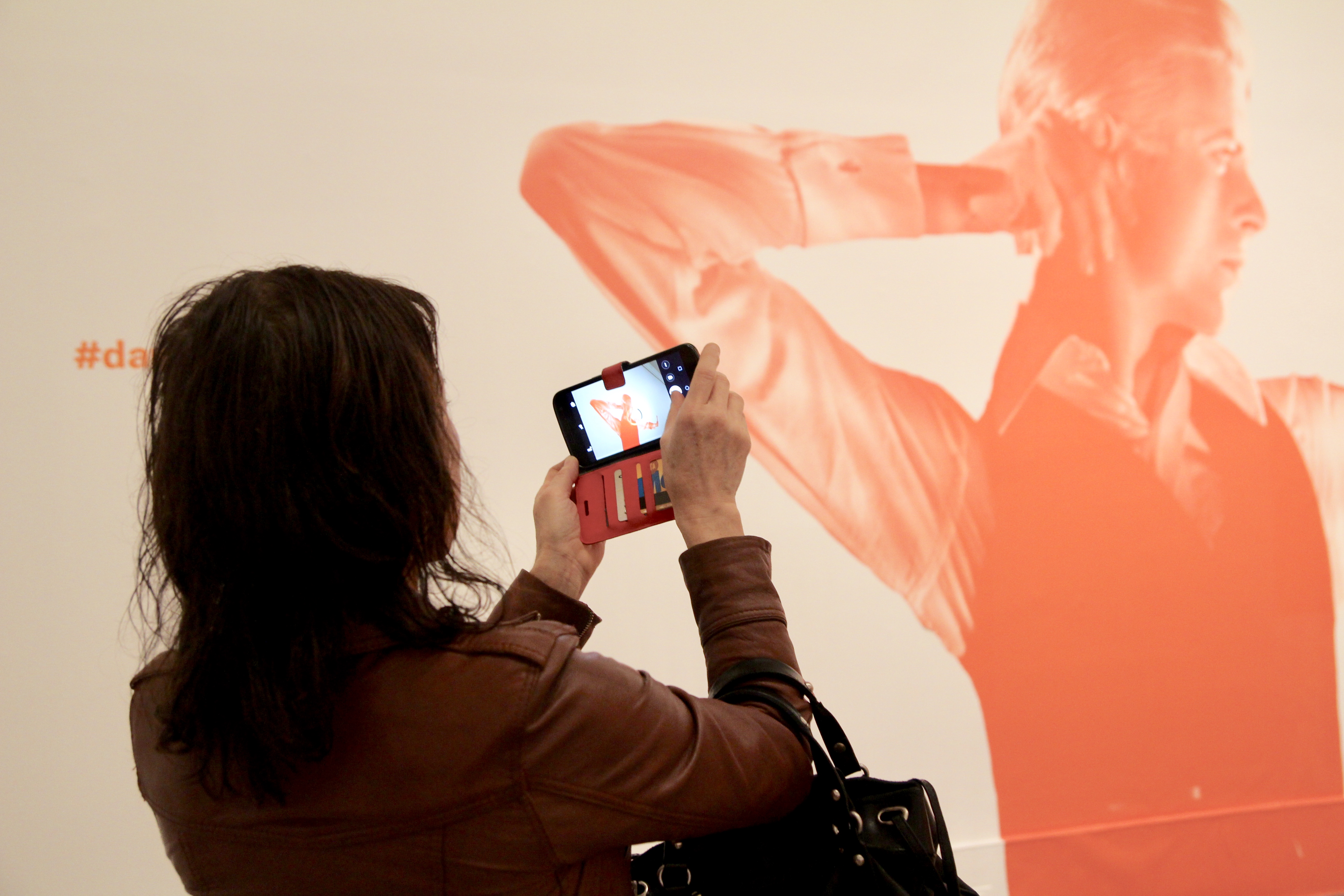 Woman snaps picture of David Bowie wall decoration