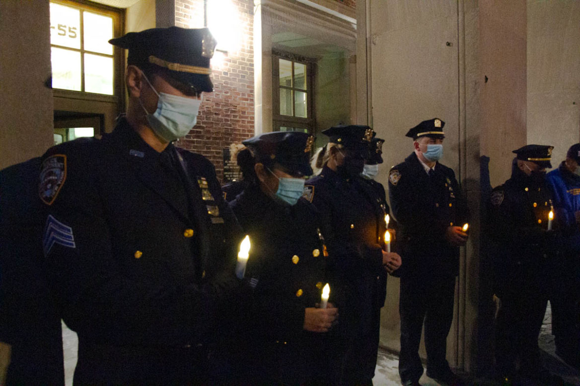 Feb. 2, 2022. NYPD officers hold lights during the vigil in Queens in honor of the two police officers died on duty. (Photograph by Eleonora Francica for NY City Lens)