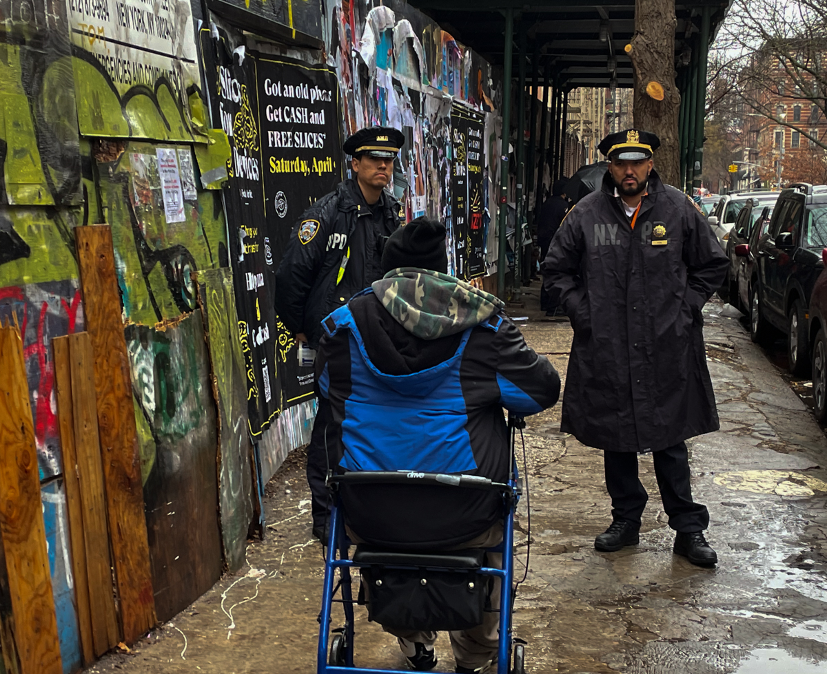 Two police officers speak with one of the men living in the row of tents on Wednesday, April 6, 2022. Credit: Luke Cregan for NY City Lens.